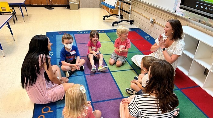 Kindergarten teachers and students during Kinder Camp in classroom on carpet